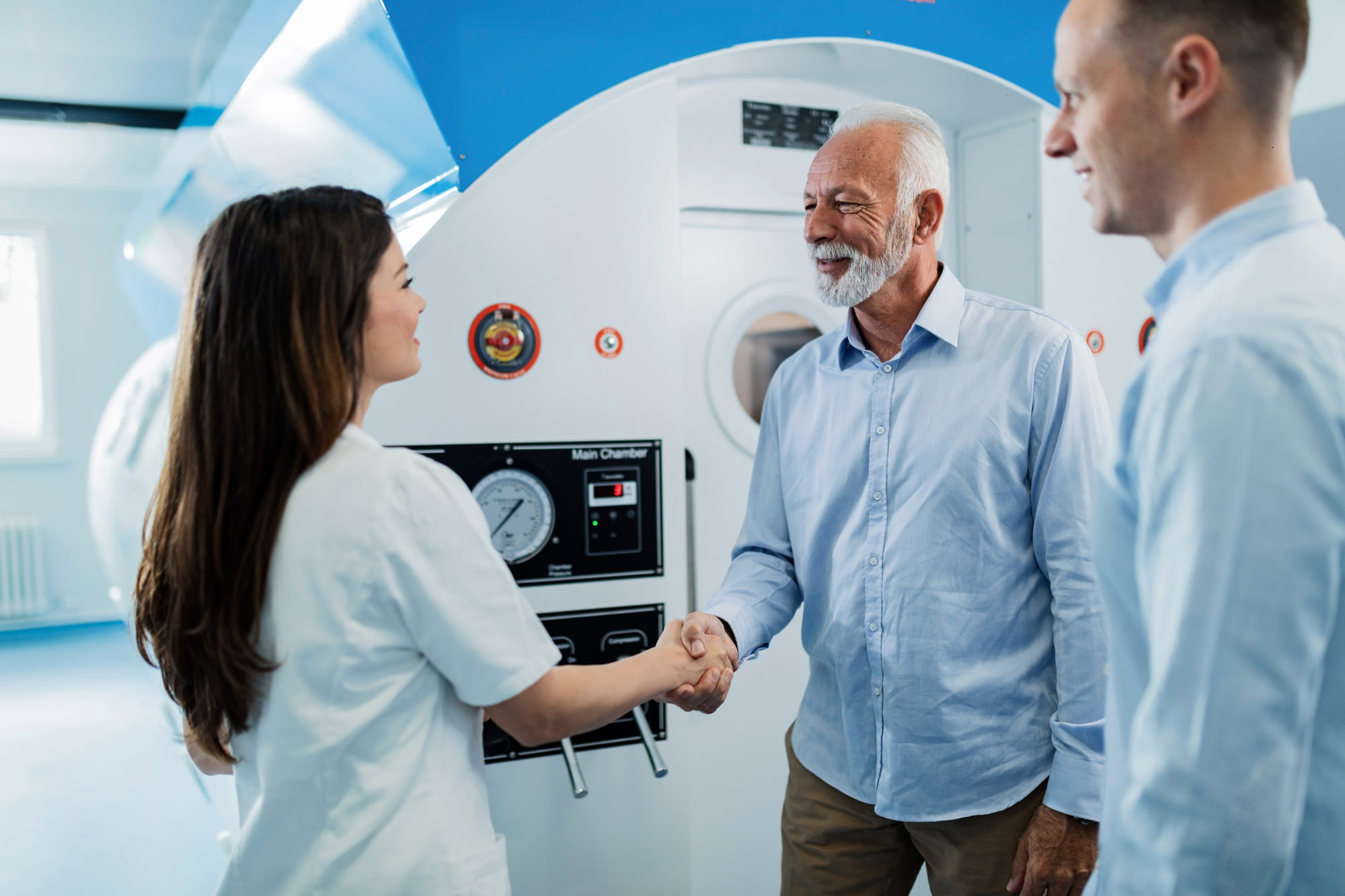 A stroke survivor with his son at his side shaking hands with a doctor in agreement to do hyperbaric oxygen therapy for stroke