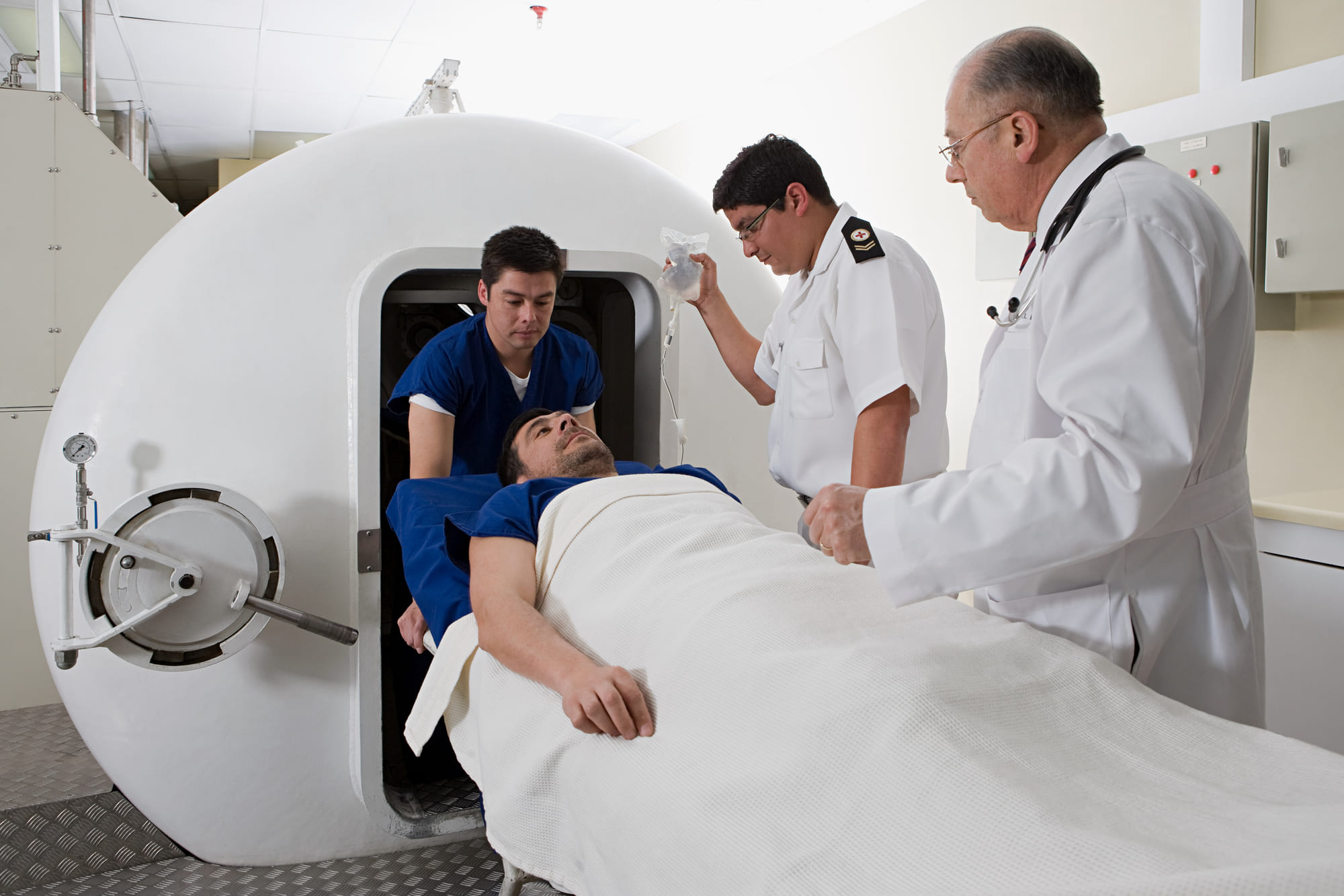 A stroke patient being assisted by a nurse into a hyperbaric oxygen therapy chamber getting treated while a doctor overlooks