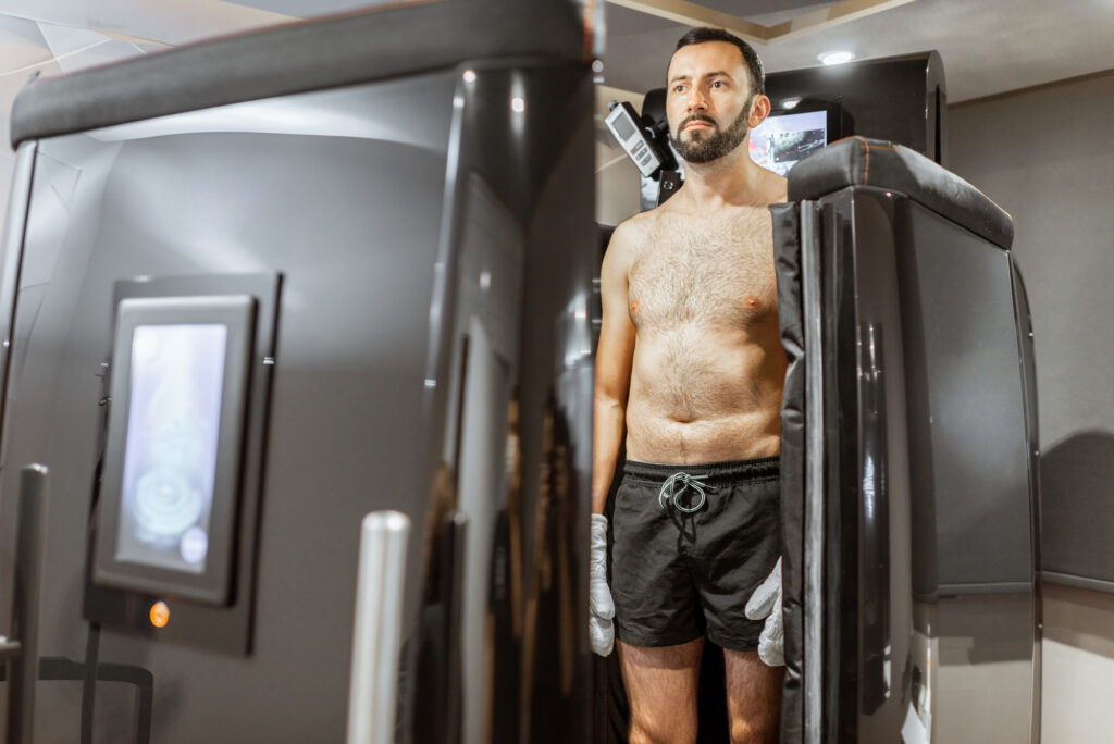 Man taking cryotherapy treatment, standing at the capsule door at a Spa salon